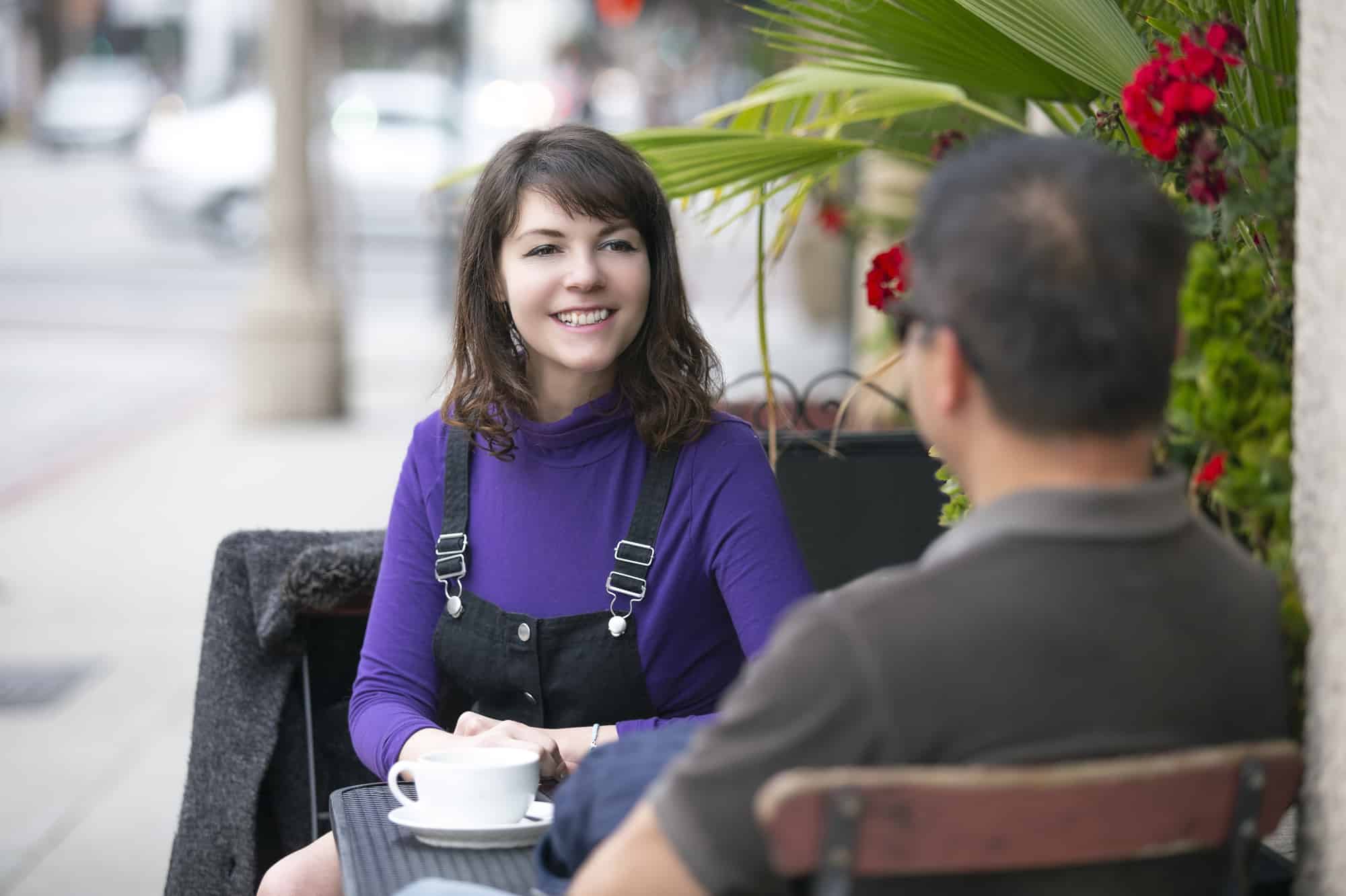 woman talking to a man at a cafe table