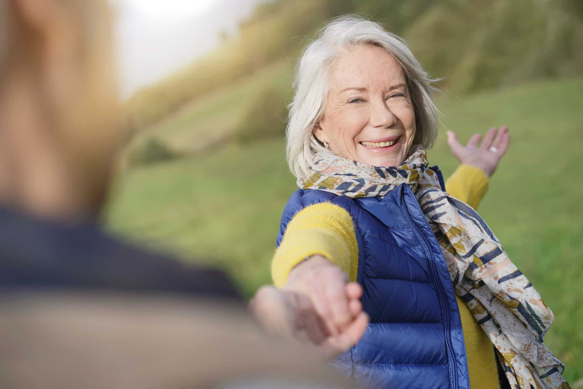an older woman smiling and holding out her hand