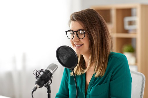 a young woman with glasses talks into a microphone