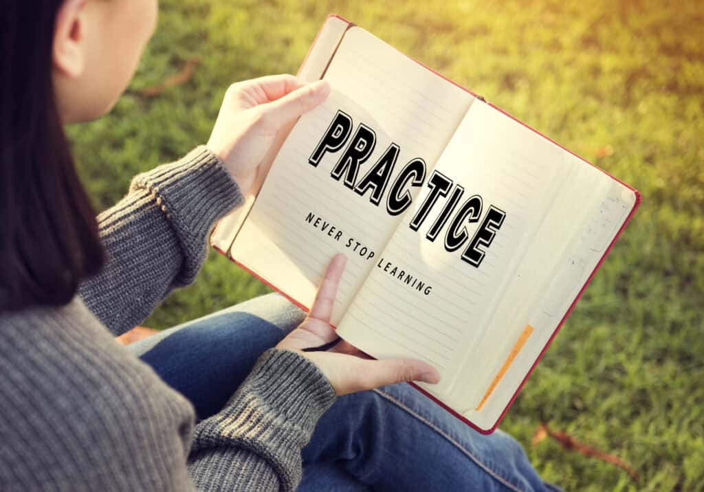 A GIRL READS A BOOK THAT SAYS "PRACTICE - NEVER STOP LEARNING"